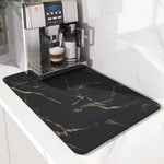 Coffee machine with a black marble-patterned mat on a white countertop