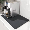 Stainless steel espresso machine on a white countertop with a black mat underneath.