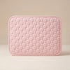 A light pink rectangular quilted cushion with a raised circular bubble pattern and rounded corners, shown against a neutral beige background.