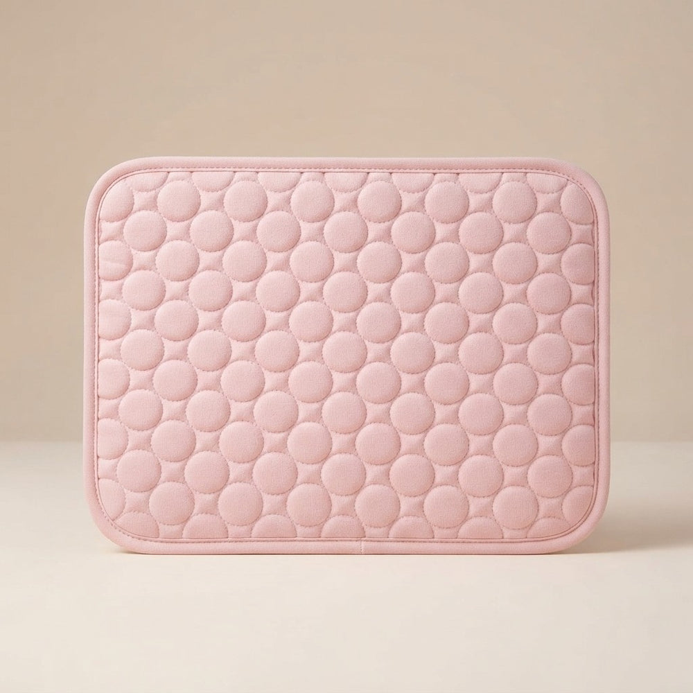 A light pink rectangular quilted cushion with a raised circular bubble pattern and rounded corners, shown against a neutral beige background.