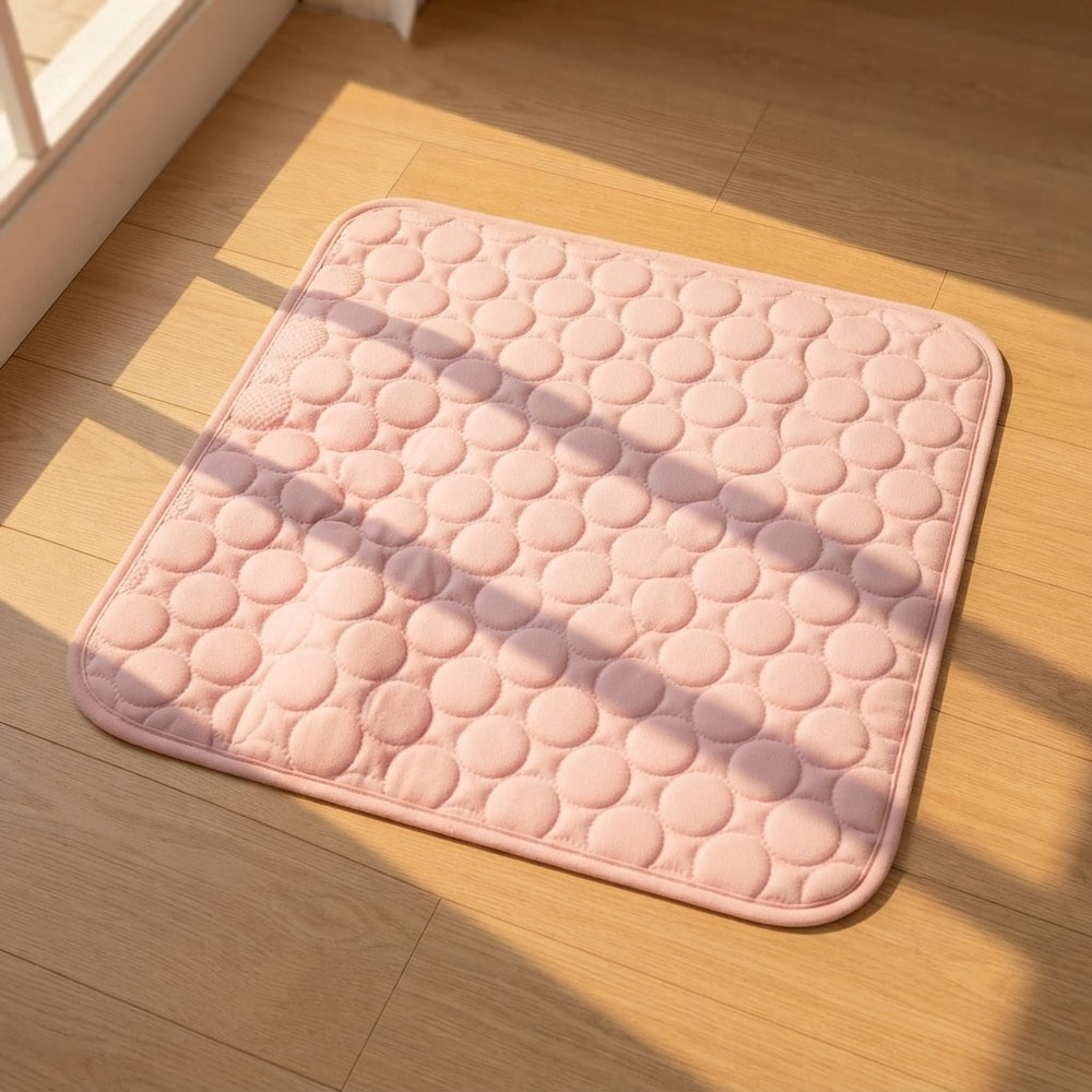 A square pink quilted cushion pad with a raised circular pattern, placed on a light wood floor in warm sunlight with soft shadows.