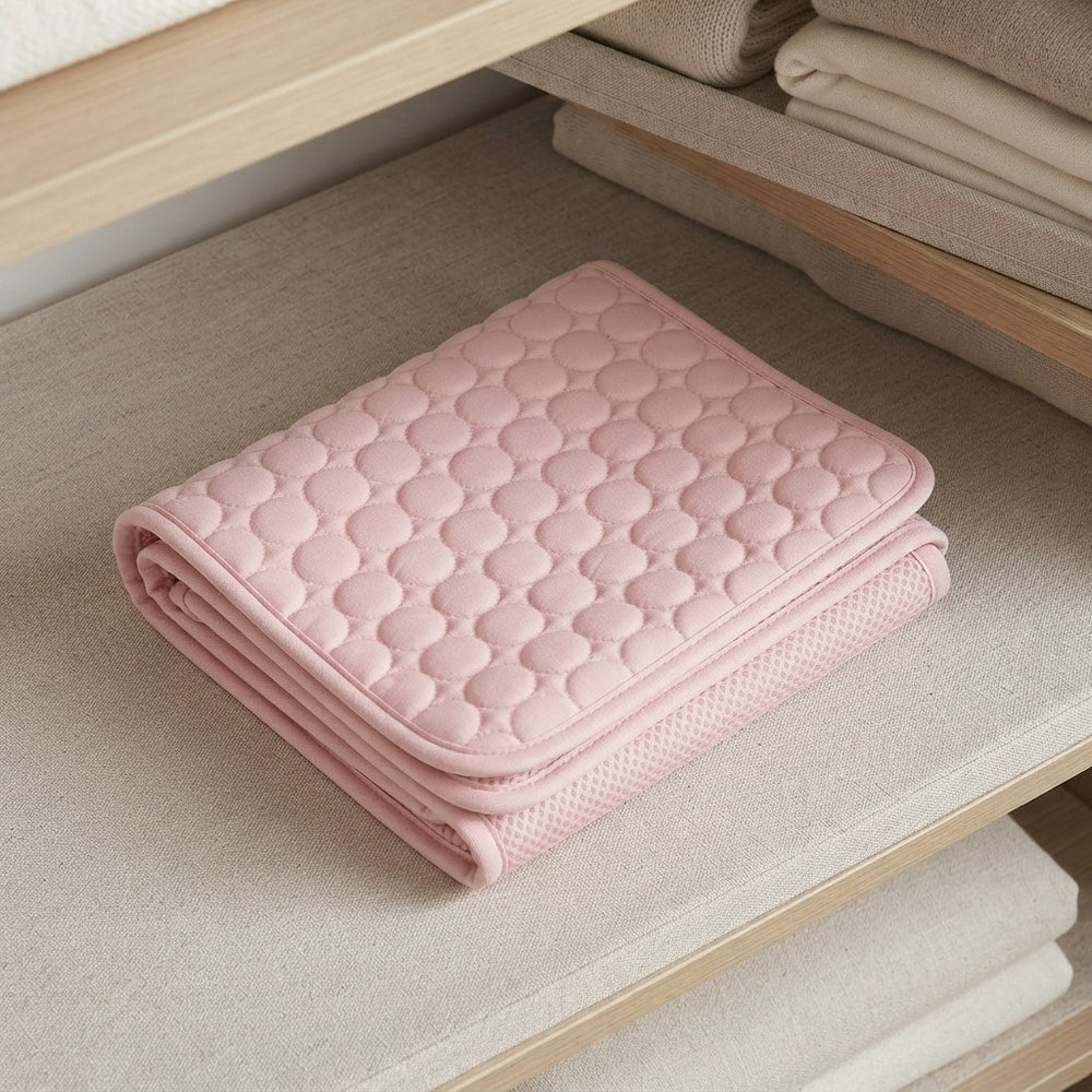 A folded light pink quilted cushion or mattress topper with a textured honeycomb pattern, resting on a beige fabric shelf.